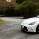 a white nissan fairlady z nismo parked at the edge of a mountain road in japan in the autumn